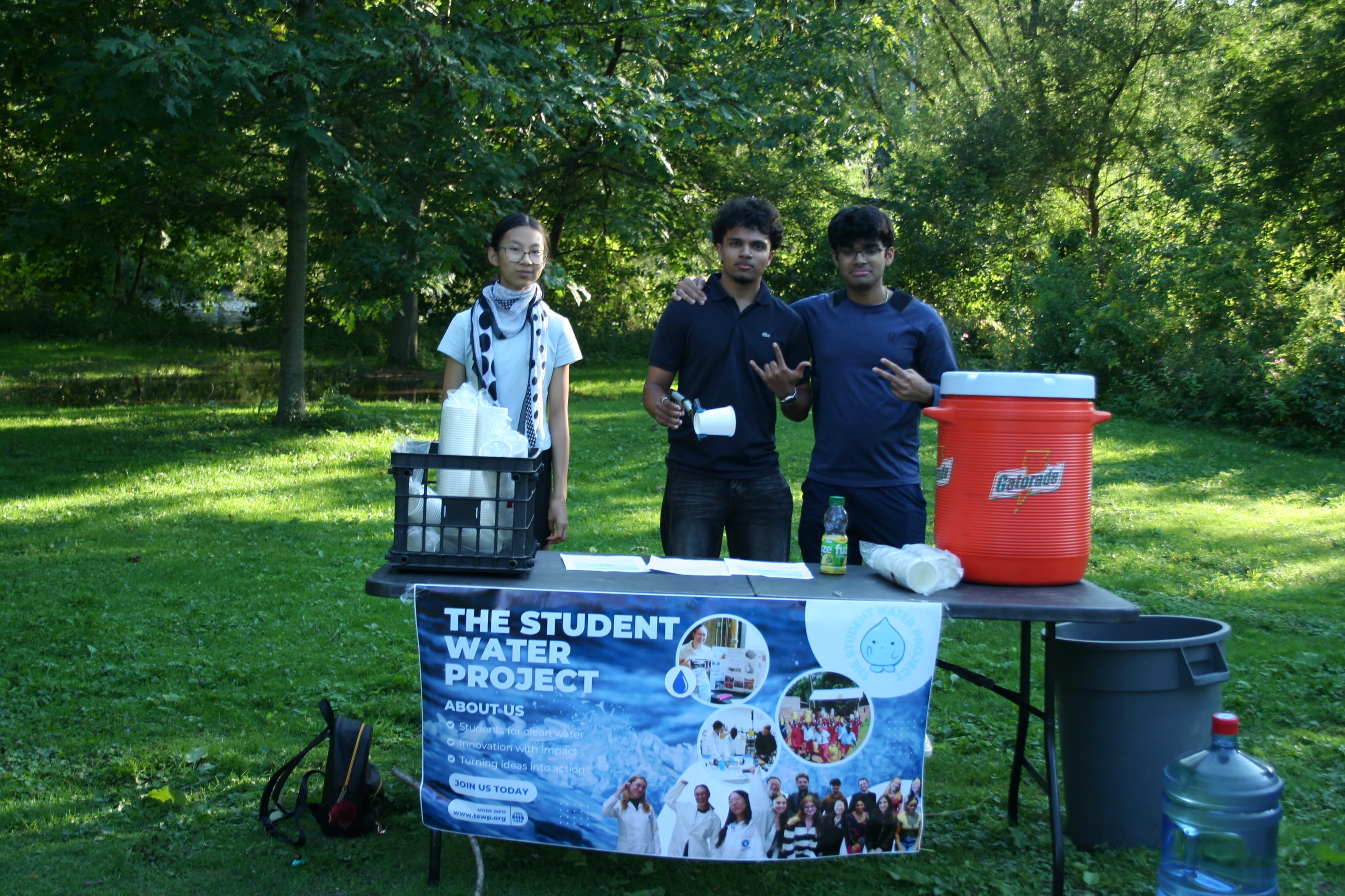 Three volunteers posing at The Student Water Project's water station booth