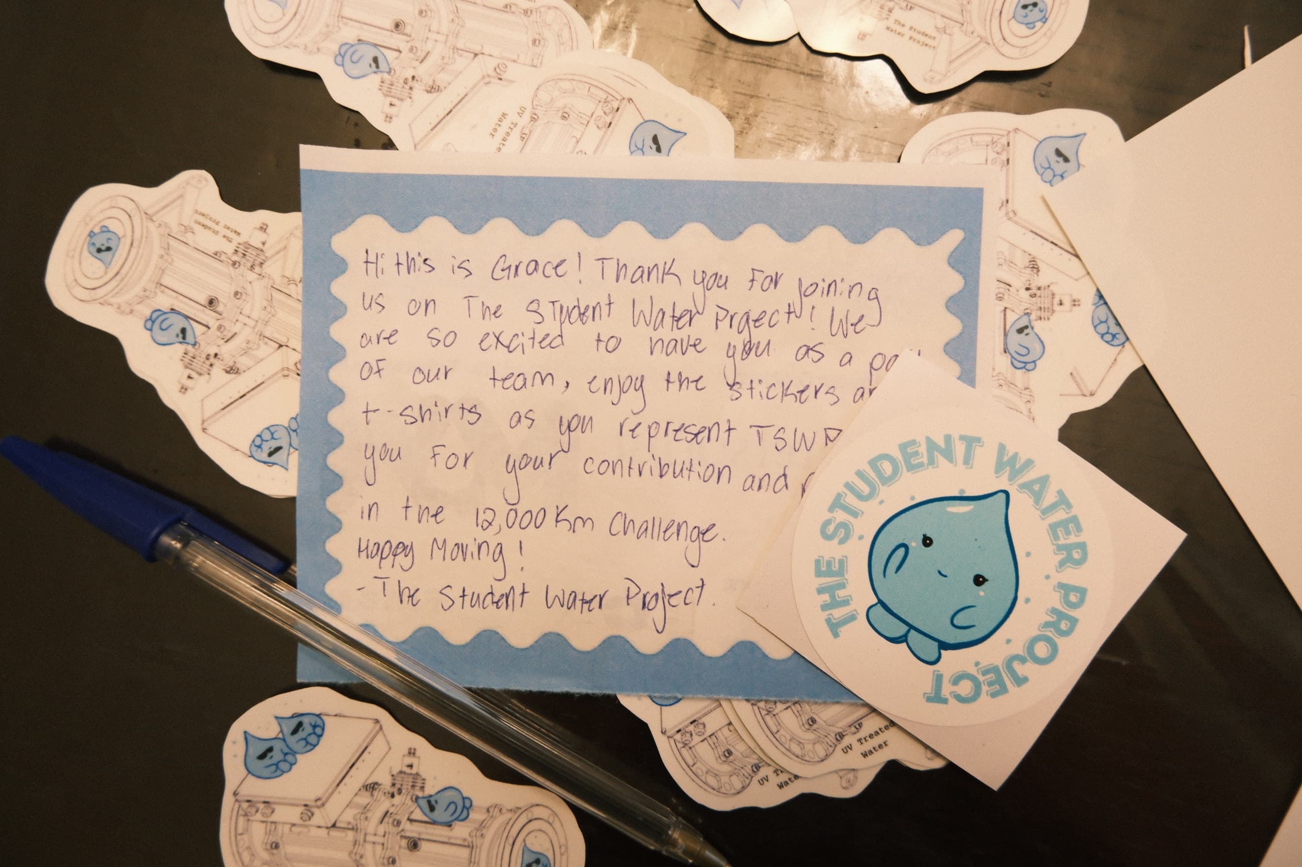 A handwritten thank-you card and stickers from The Student Water Project